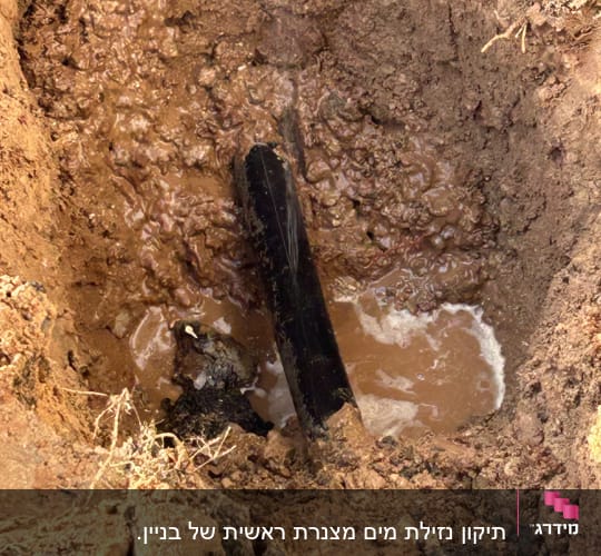 צינור מים שבור בתוך בור אדמה רטוב